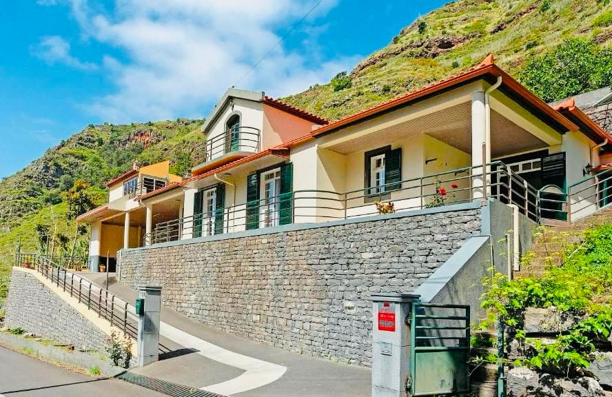 Façade de la maison au toit rouge, adossée à la montagne